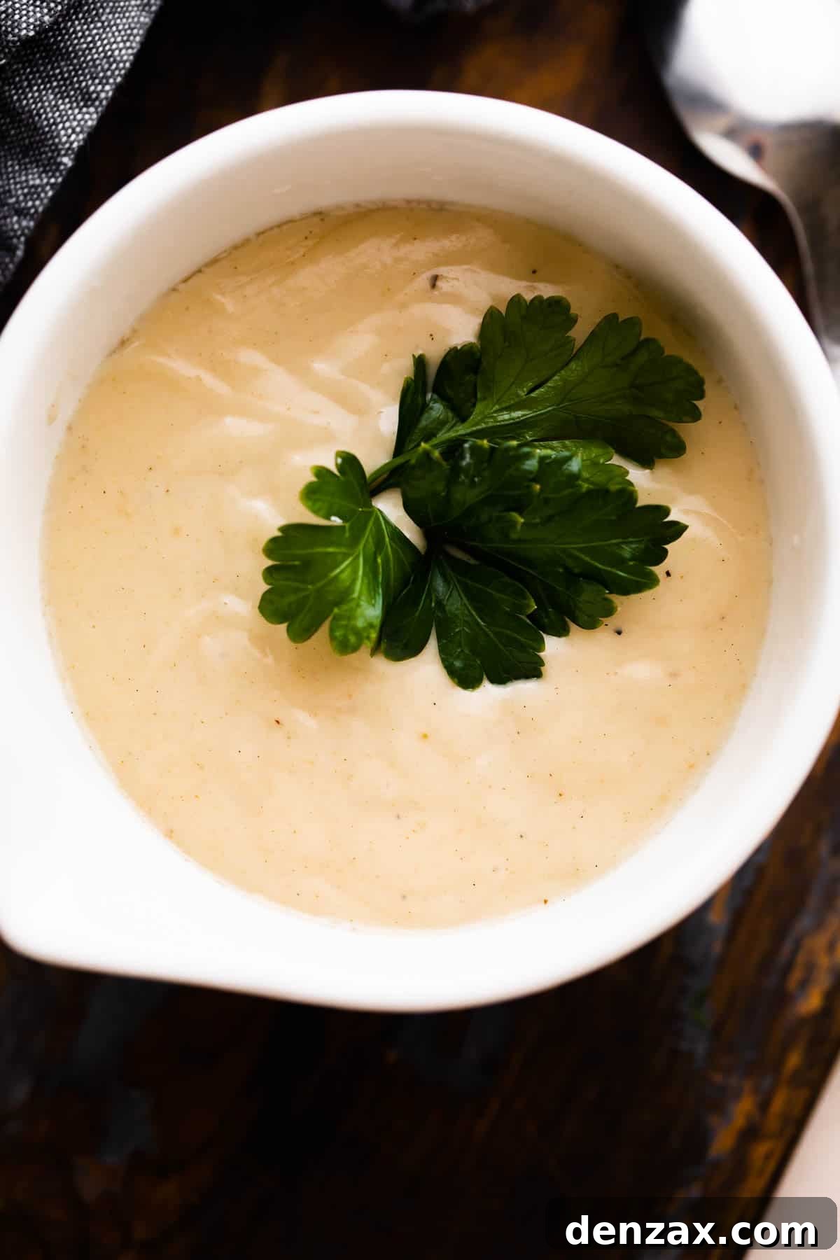 overhead shot of a white ceramic cup filled with homemade cream of chicken soup