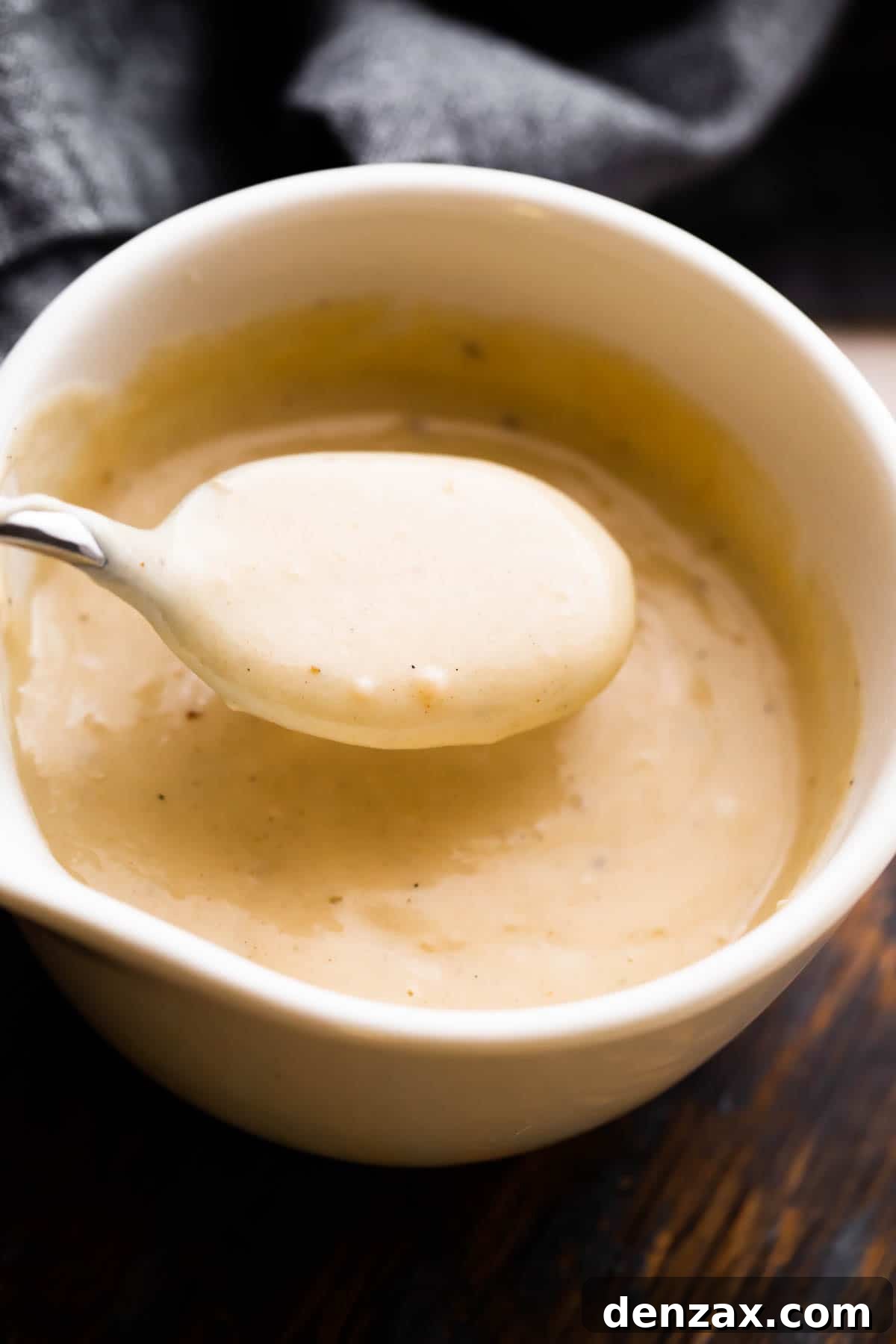 overhead shot of a white ceramic cup filled with homemade cream of chicken soup and a spoon scooping out the soup.