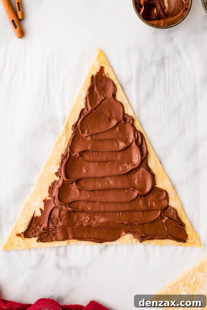 A triangle of puff pastry dough, spread with hazelnut spread.
