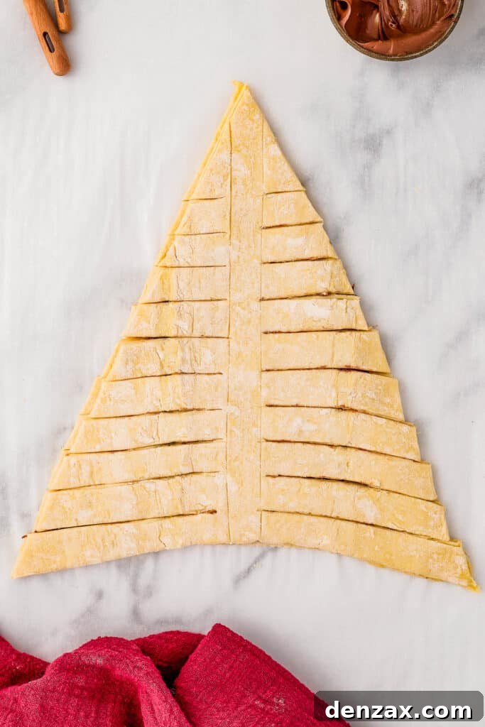The cut-out triangle of puff pastry, filled with Nutella, with horizontal cuts along either side.