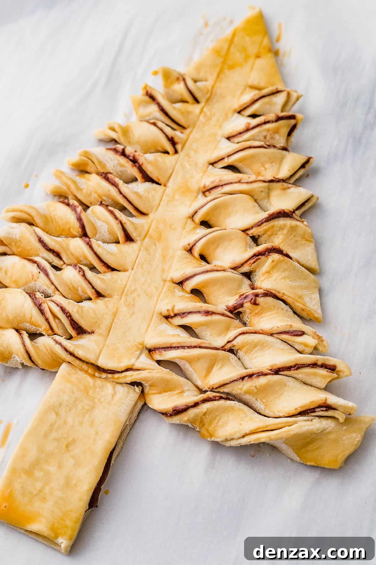 The unbaked puff pastry tree, with the horizontal strips twisted to show the filling.