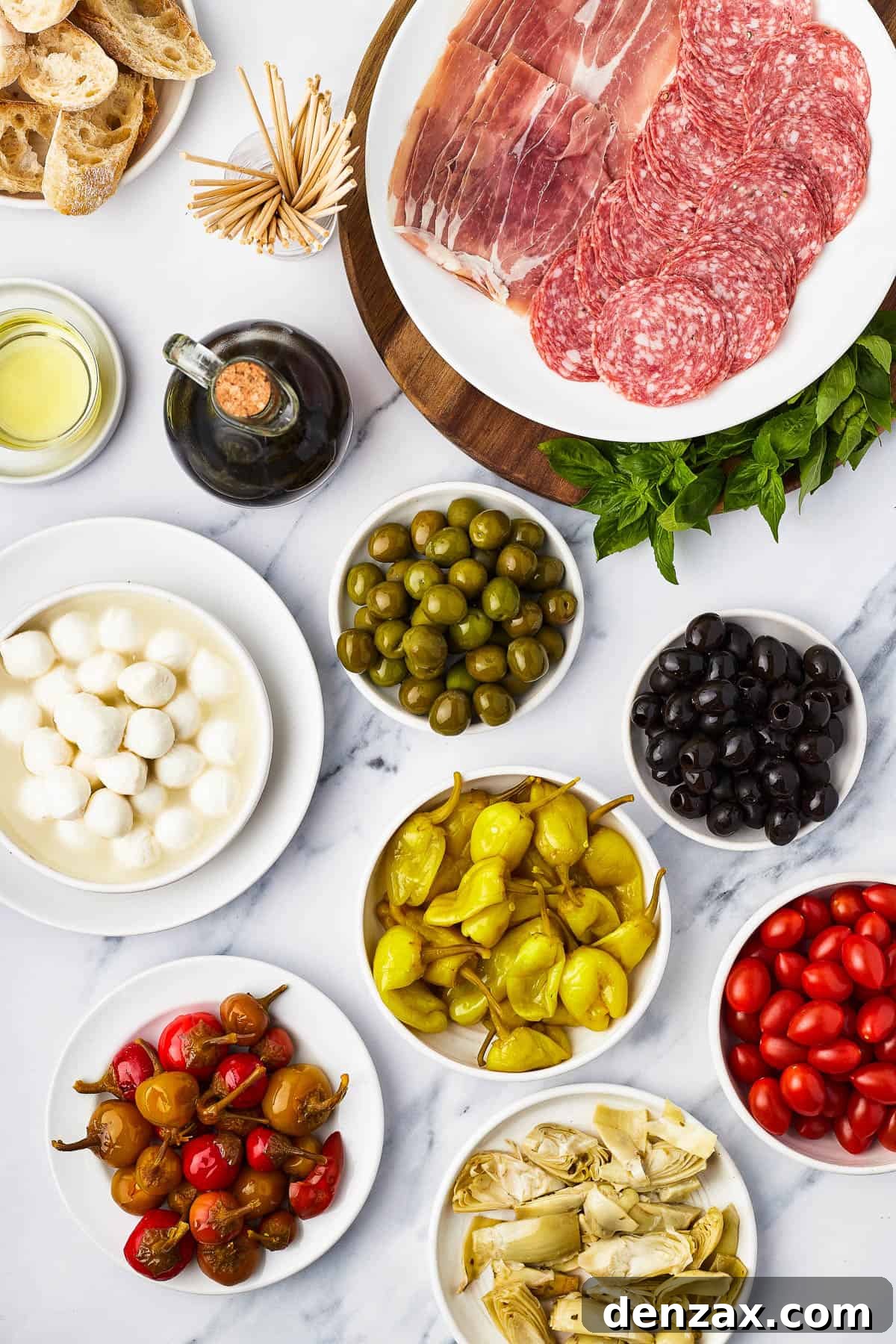 Clockwise from top: Salami and prosciutto slices, green olives, black olives, grape tomatoes, artichoke hearts, pepperoncini, sweet cherry peppers, mozzarella balls, balsamic vinegar, oil, sliced bread.