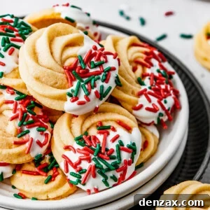 A small dessert plate stacked on top of several other plates, and piled with iced butter cookies.