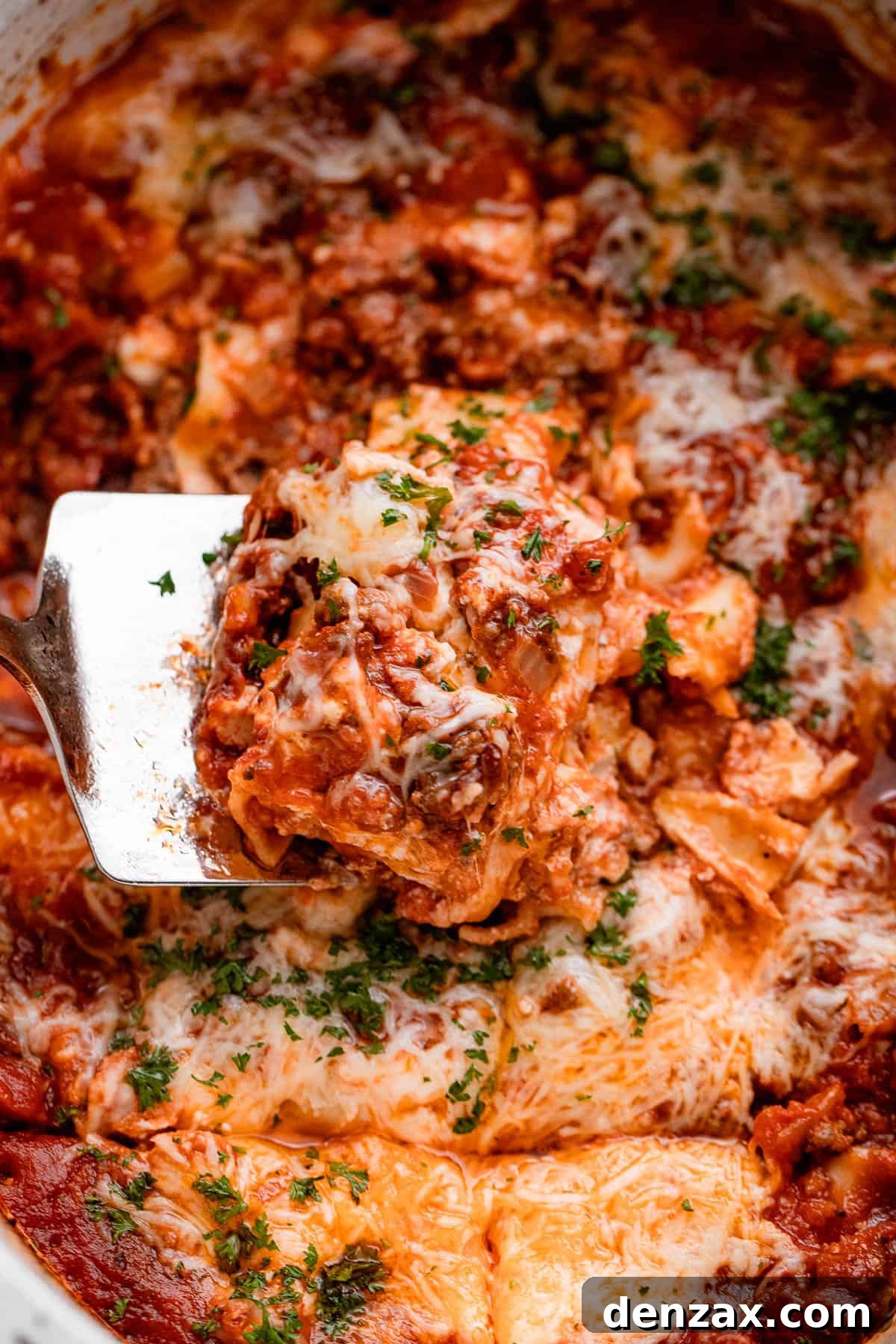 up close shot of a spatula lifting up a piece of lasagna from the slow cooker.