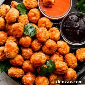 overhead shot of popcorn chicken arranged on a black plate with bowls of buffalo sauce and barbecue sauce placed right next to it.