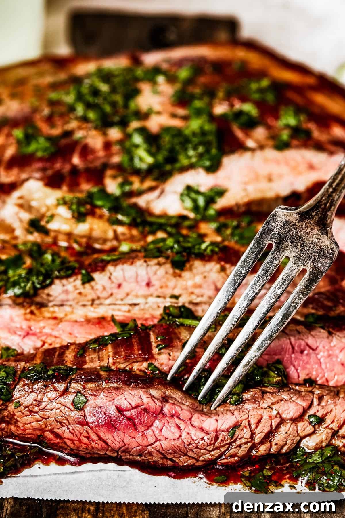 Side view of sliced flank steak with a fork.