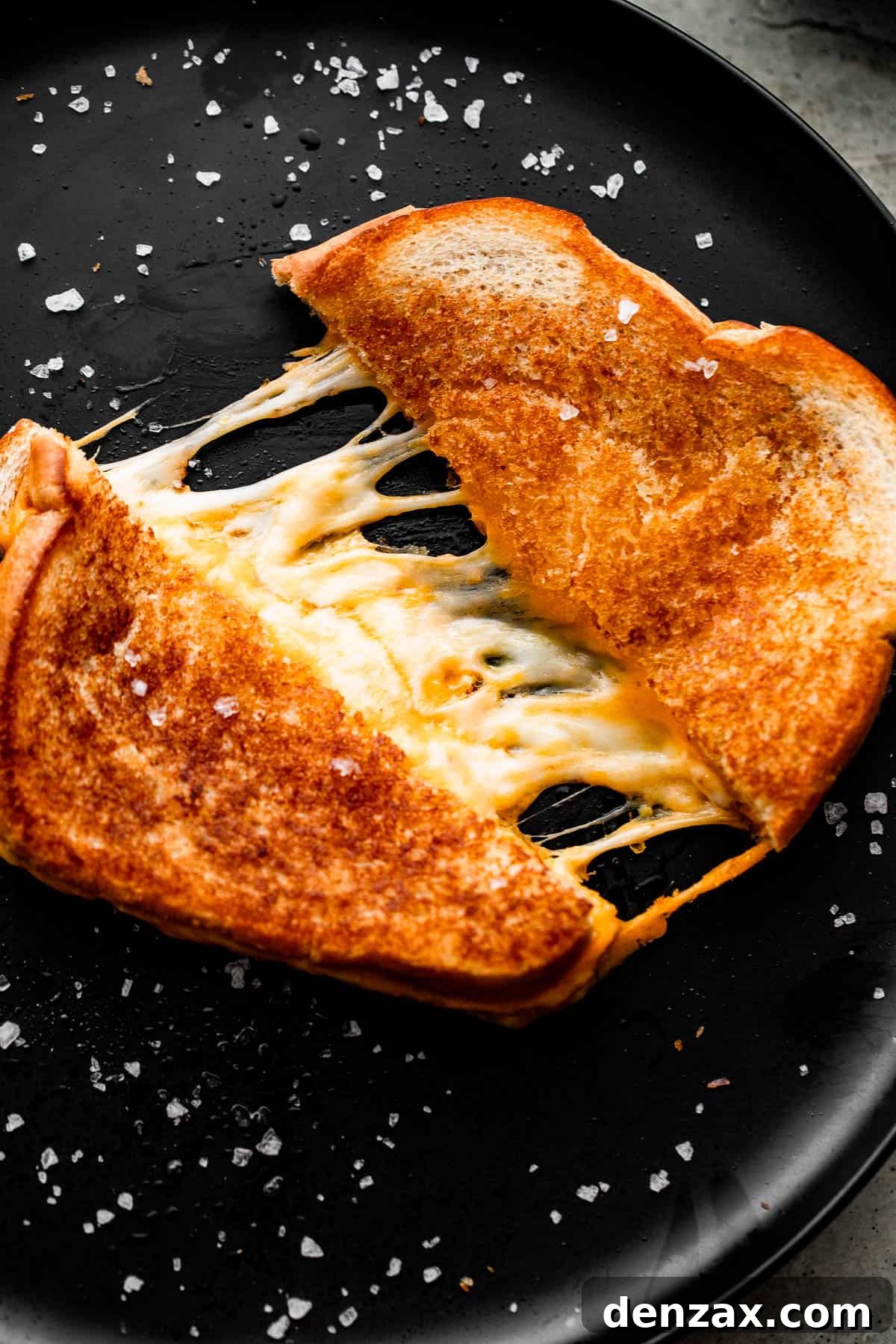 baked grilled cheese sandwich cut and pulled apart, with melted cheese tearing through the center.