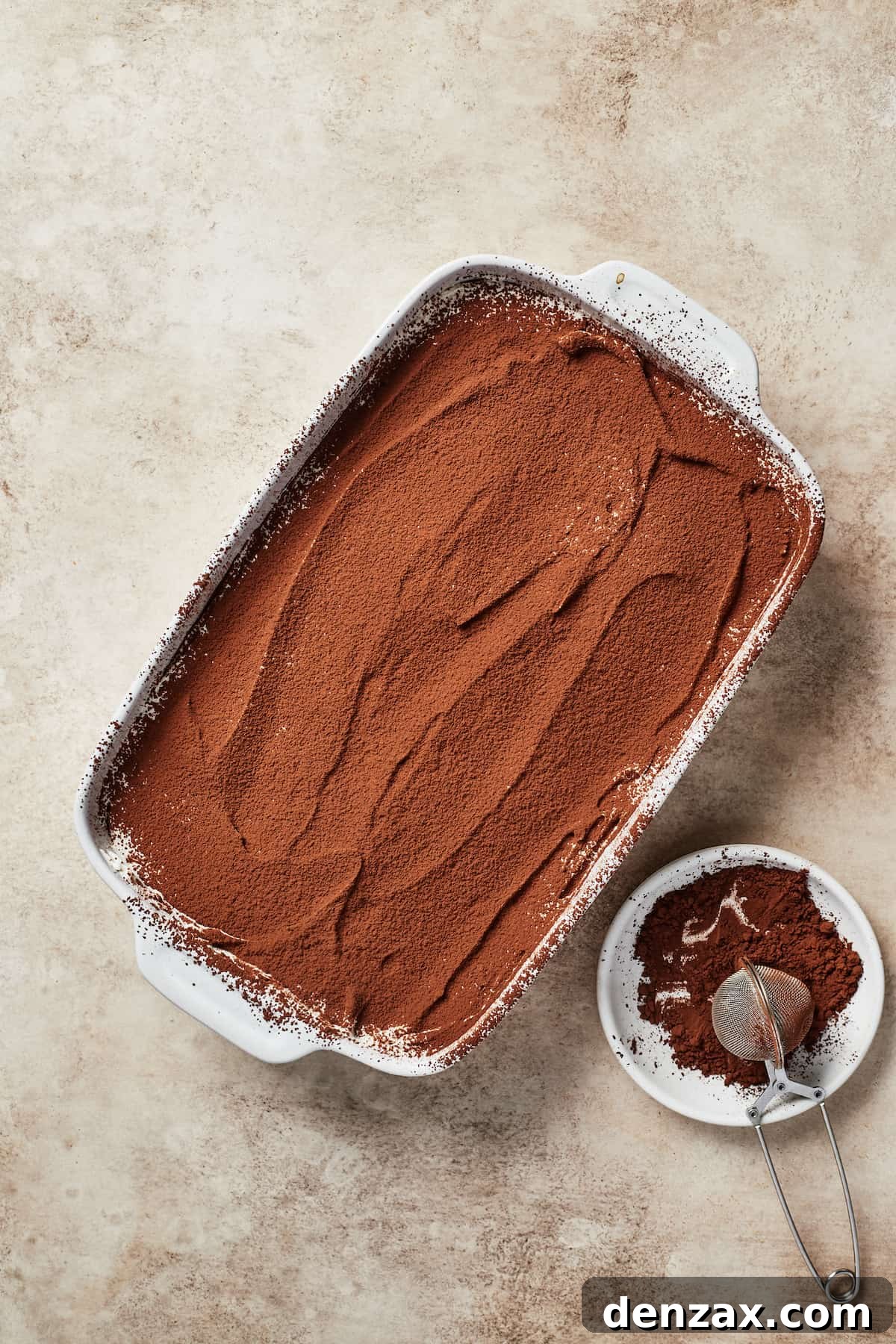 A baking dish with a cocoa-powder topped dessert.