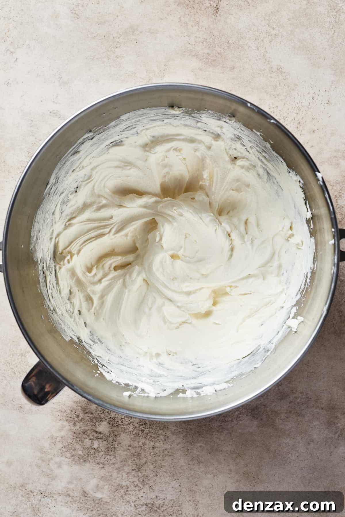 A metal mixing bowl filled with a creamy mixture.