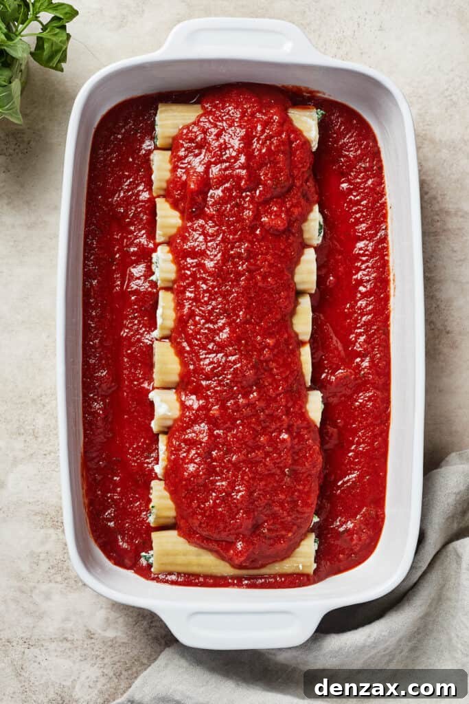 Uncooked pasta in a baking dish, covered in marinara.