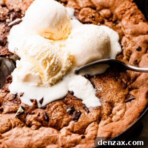 close up overhead shot of three vanilla ice cream scoops set on top of a large skillet cookie.