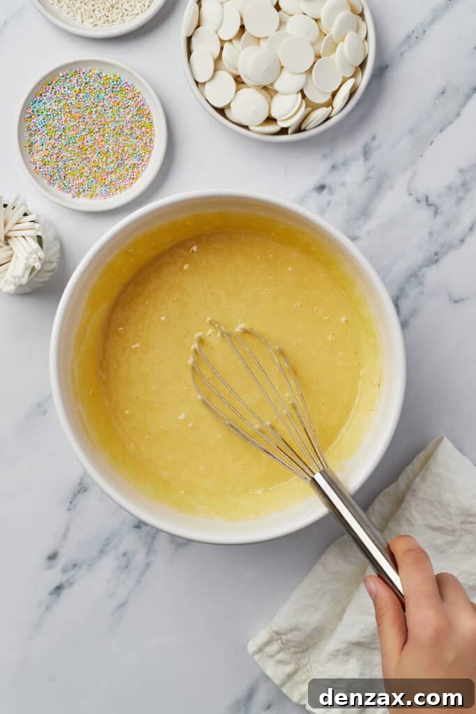 Yellow cake batter in a mixing bowl with a whisk.