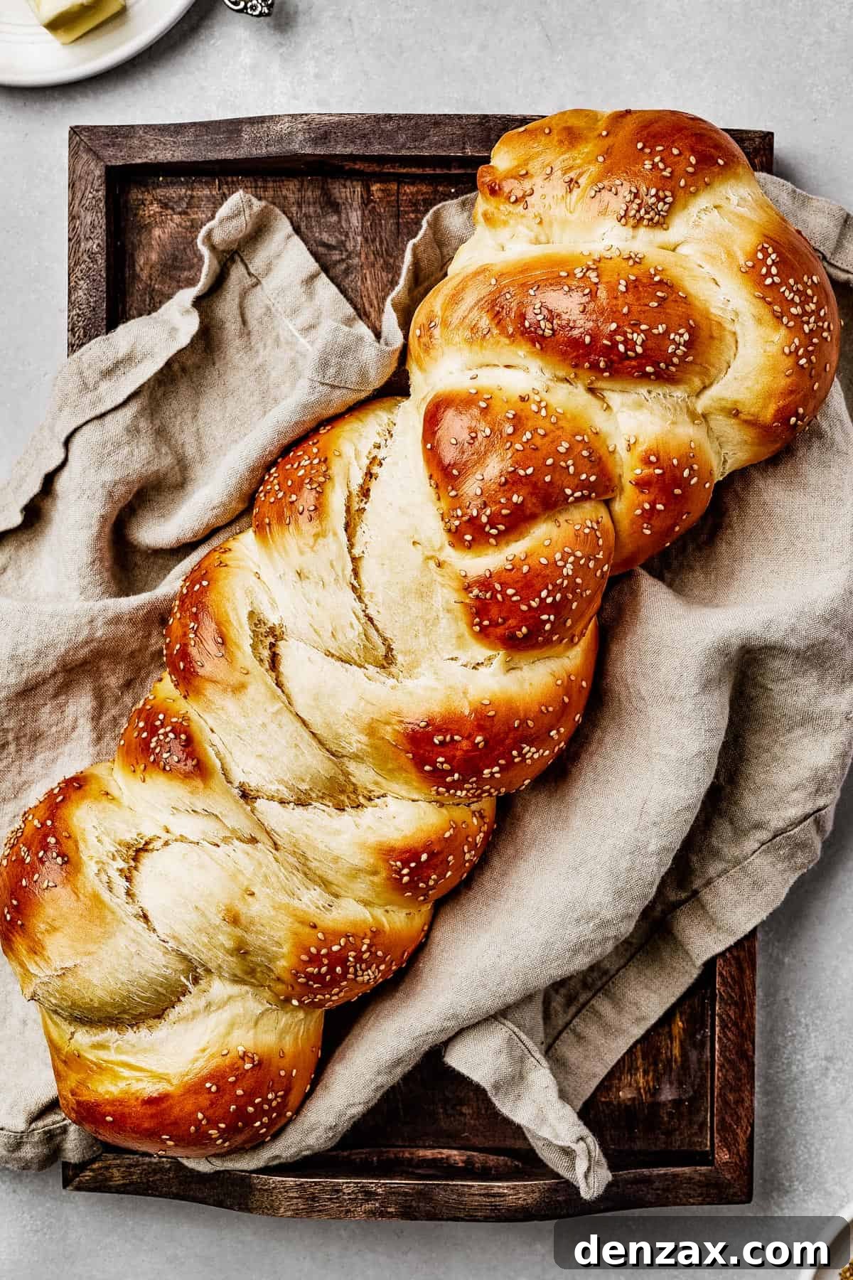 Classic Homemade Challah Recipe: Soft, Fluffy Braided Bread 2 Baked challah with sesame seeds, on a sheet pan with a tea towel.