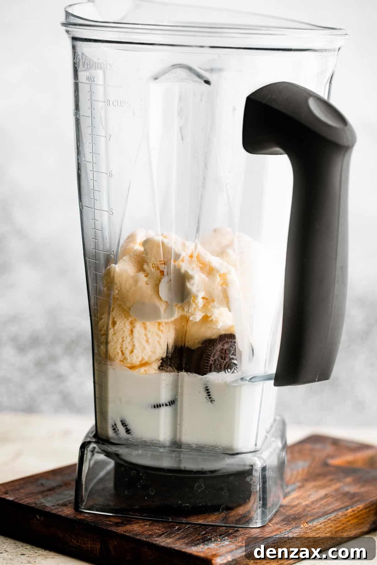 jar of a blender filled with milk, heavy cream, ice cream, and oreo cookies.