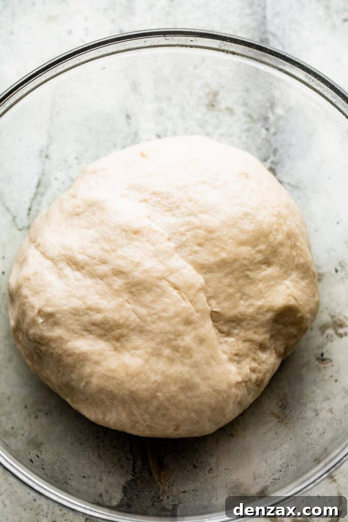 a glass bowl with a ball of bread dough.