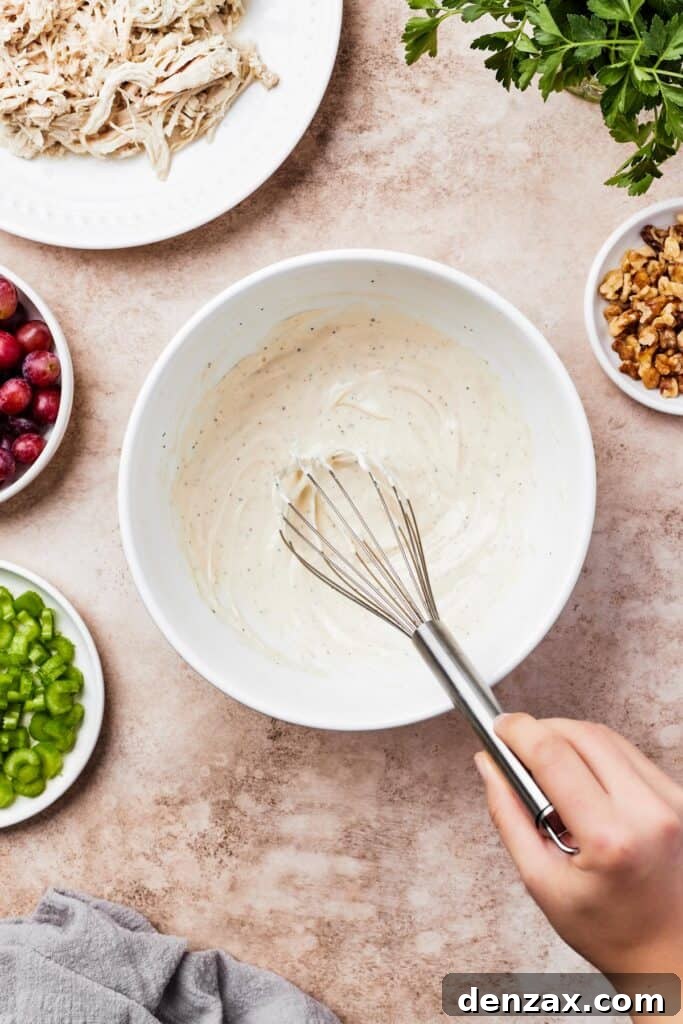A small mixing bowl with creamy sauce in the bottom. A woman is whisking the sauce.