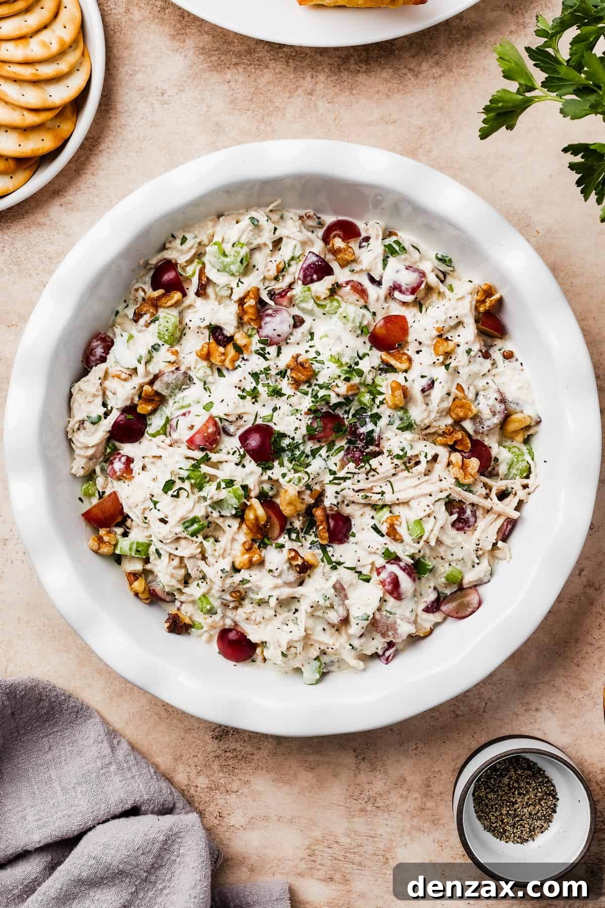 A shallow white dish filled with creamy chicken salad, garnished with nuts.