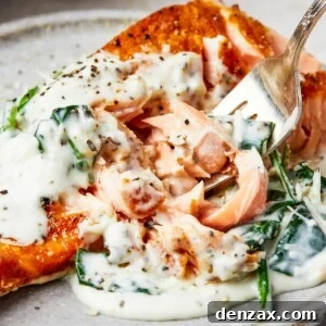 A serving of salmon florentine. A bite of the salmon is being lifted toward the camera on a fork.