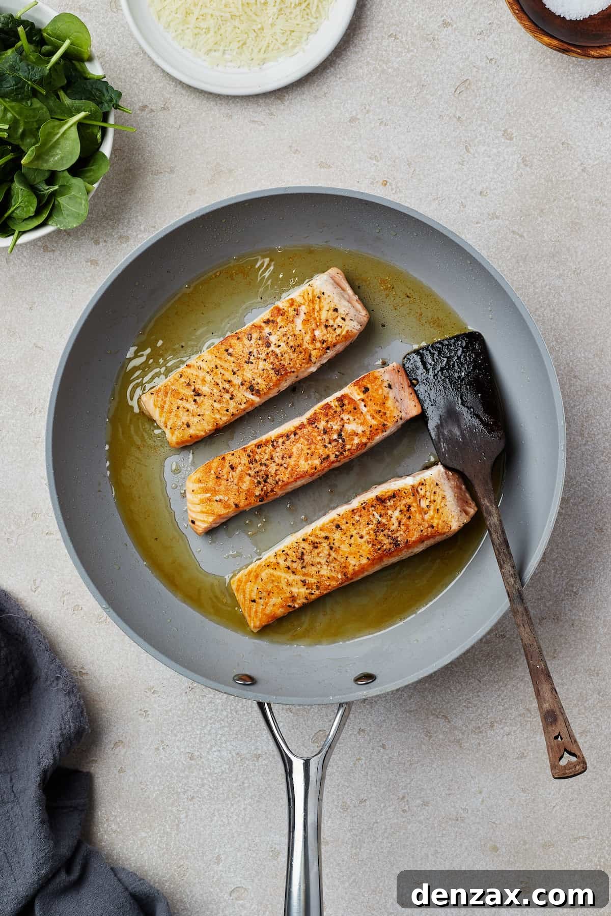 Salmon fillets cooking in a skillet.