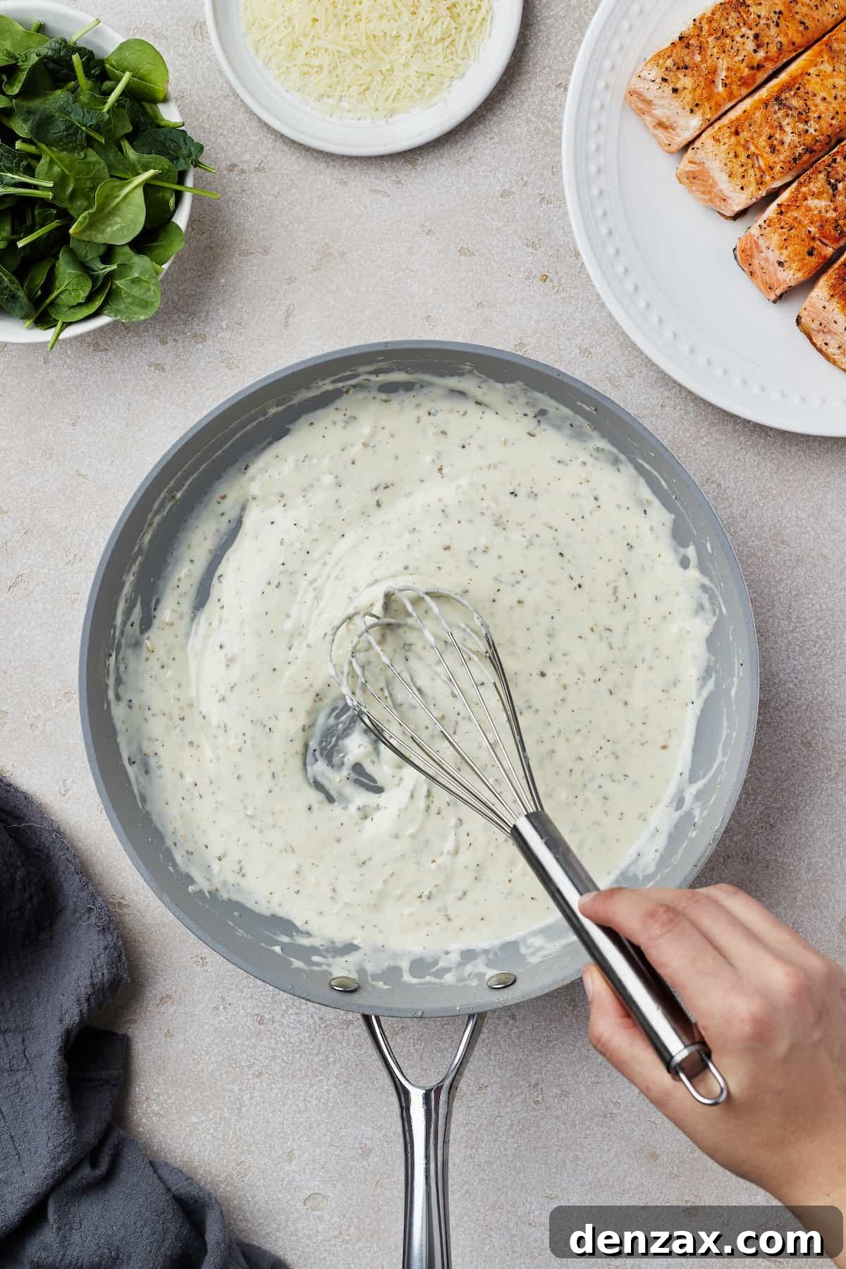 Creamy sauce being whisked in a skillet.