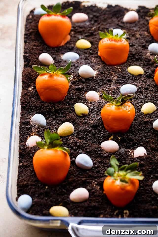 Oreo Dirt Cake topped with chocolate covered strawberries and chocolate egg candy