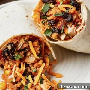 Easy Instant Pot Chicken Burritos Recipe — Quick & Flavorful Meal 13 Two chicken burritos on a plate with lime wedges. The filling is spilling out of one of the halves onto the plate.