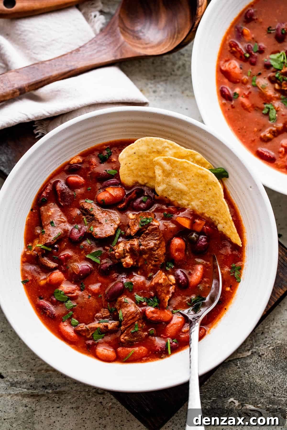 Chili con Carne served in two white bowls, and a couple of tortilla chips set inside the bowls.