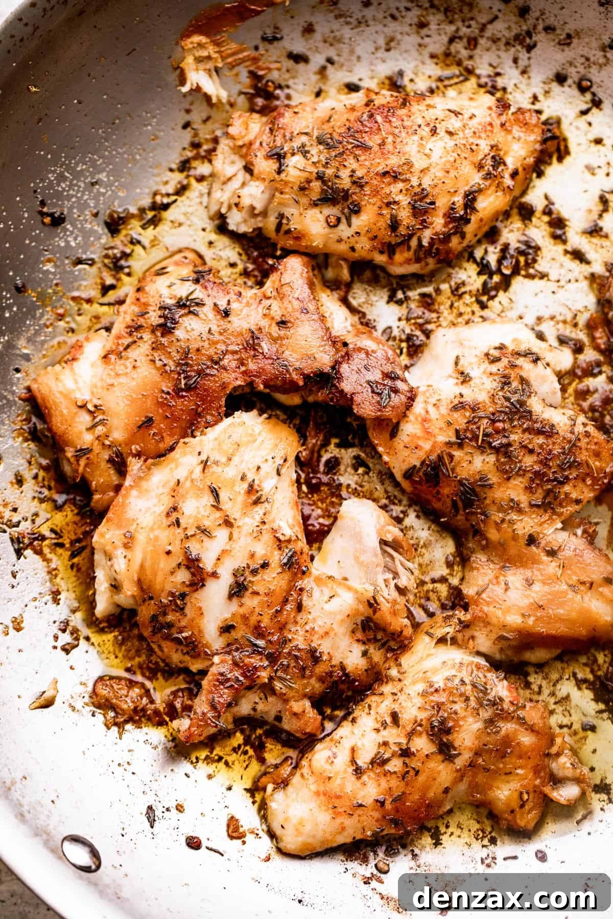 browned boneless chicken thighs seasoned with spices and herbs and set in a skillet.