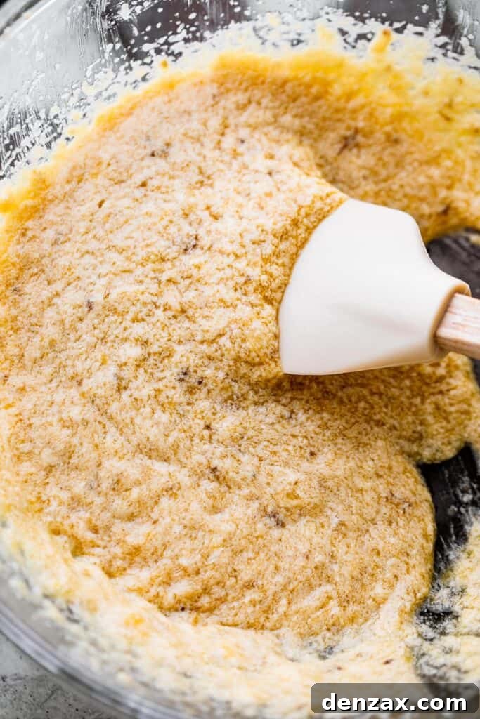 rubber spatula stirring through liquid batter for banana cookies.