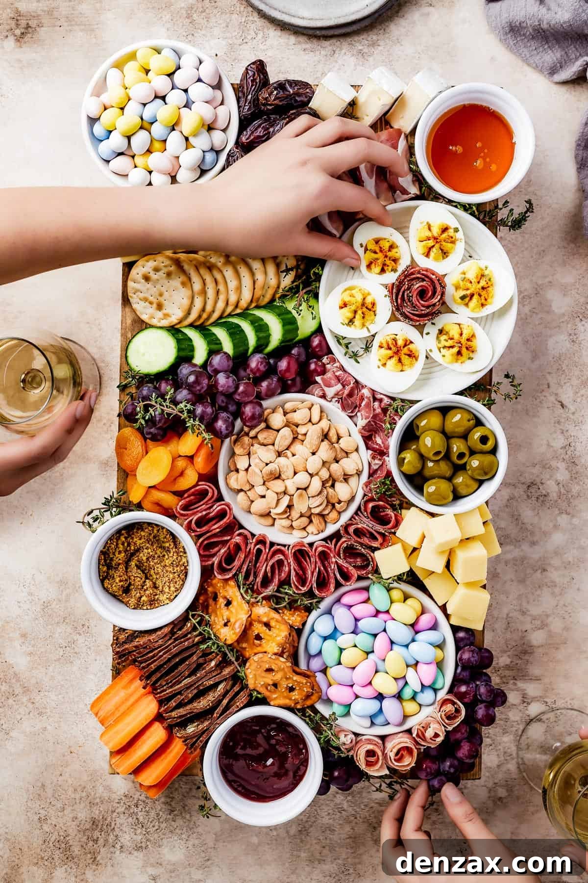 A wooden cutting board artistically arranged with meats, cheeses, crackers, olives, fruit, veggies, and more.