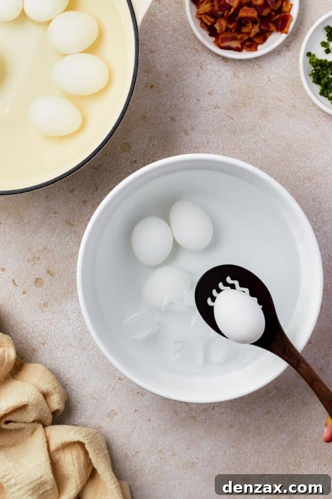 Classic Deviled Eggs Recipe: Creamy, Tangy Party Appetizer 5 A bowl of peeled hard cooked eggs in water. Nearby are a plate of eggs in the shell, and a small dish of discarded egg shells, along with a few small dishes of ingredients and a cloth napkin.
