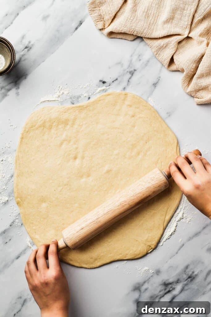Dough being rolled out on a marble work surface.