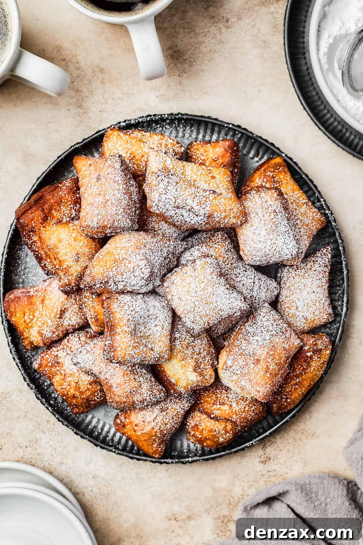 A plate of fried beignets, dusted with powdered sugar.