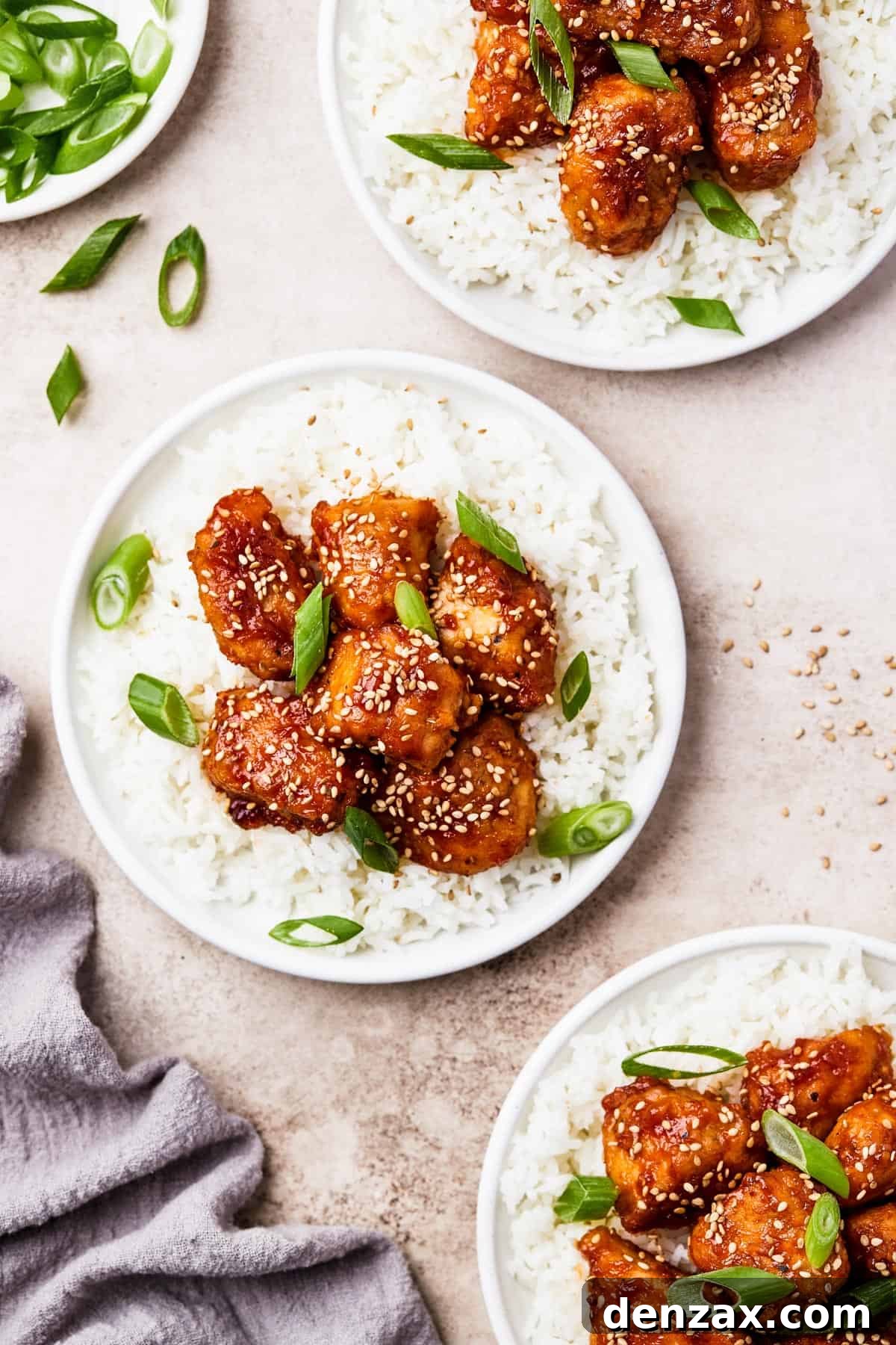 three plates topped with white rice topped with saucy chunks of chicken.