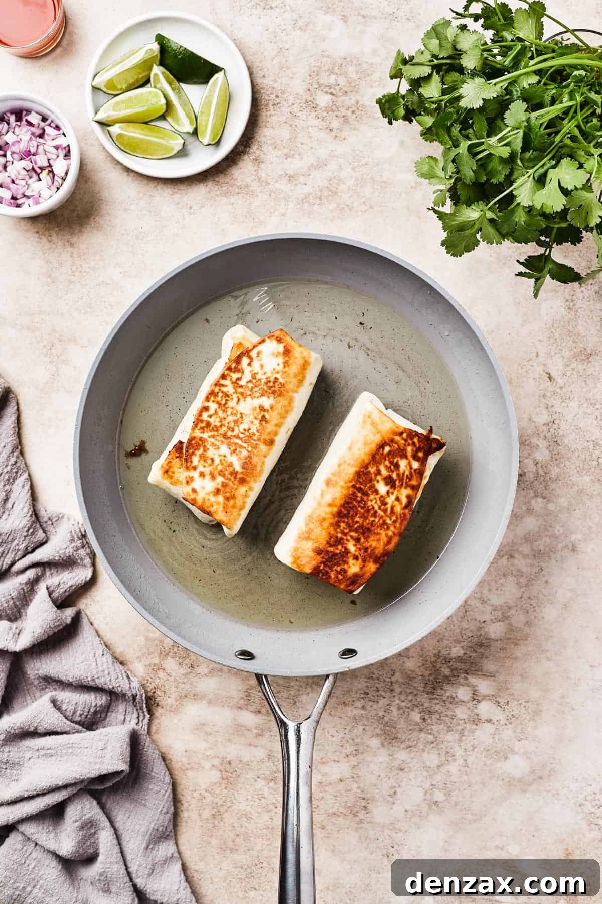 Fried burritos in a skillet with oil.
