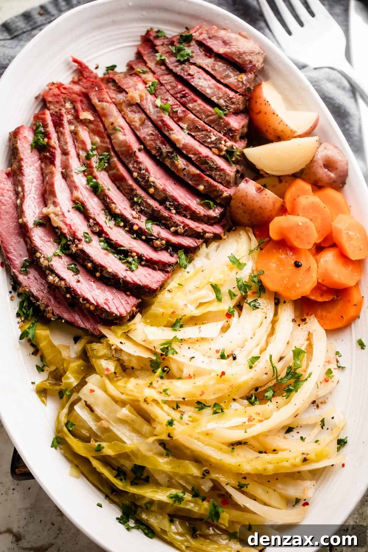 sliced instant pot corned beef, cabbage, carrots, and potatoes arranged on an oval serving platter.
