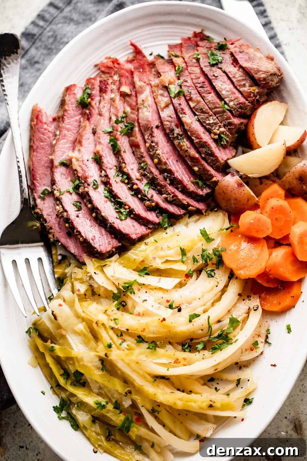 sliced instant pot corned beef, cabbage, carrots, and potatoes arranged on an oval serving platter.