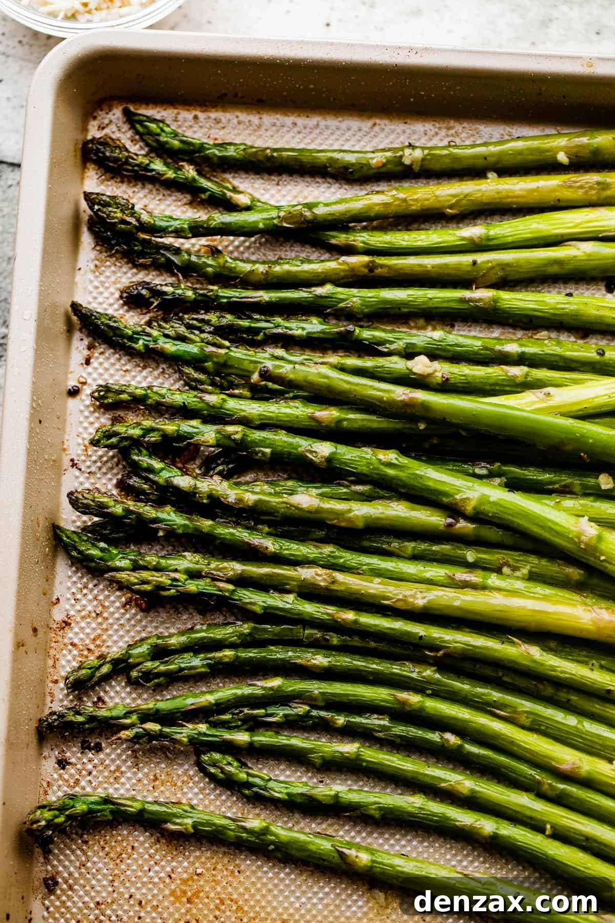 overhead shot of roasted asparagus spears on a baking sheet.