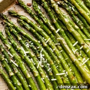 parmesan topped asparagus spears arranged on a gold-colored baking sheet.