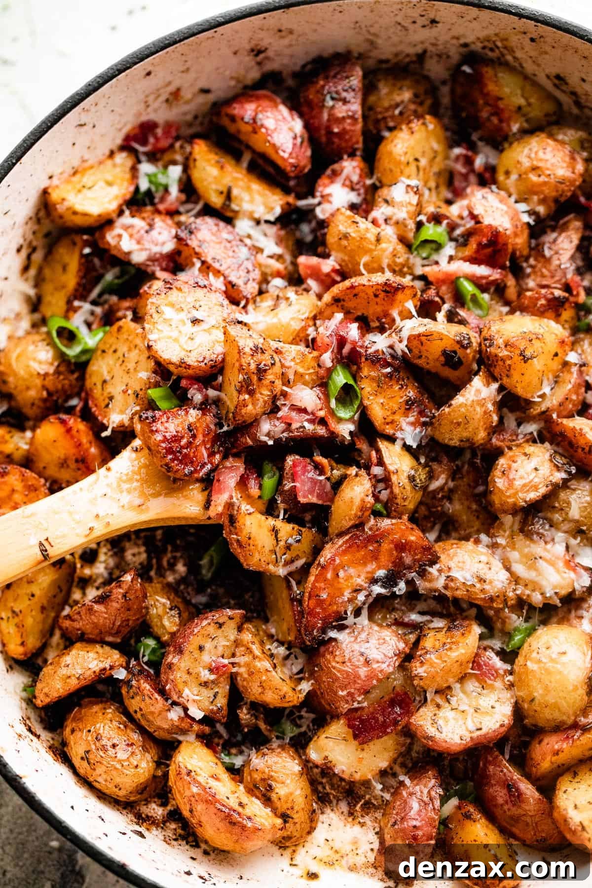 Crispy Roasted Potatoes with Bacon, Cheese, and Herbs 2 overhead shot of roasted potatoes and bacon in a white skillet.