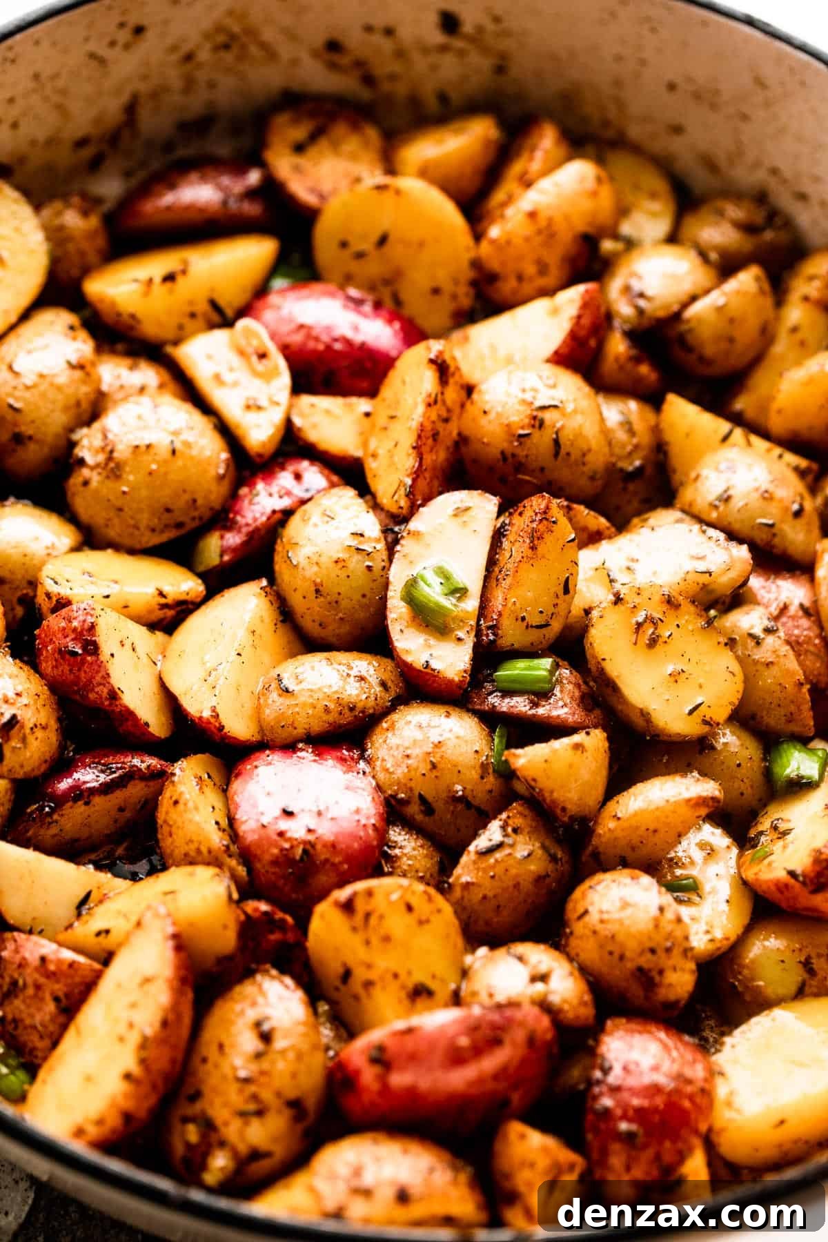 Crispy Roasted Potatoes with Bacon, Cheese, and Herbs 4 quartered small potatoes in a white skillet.