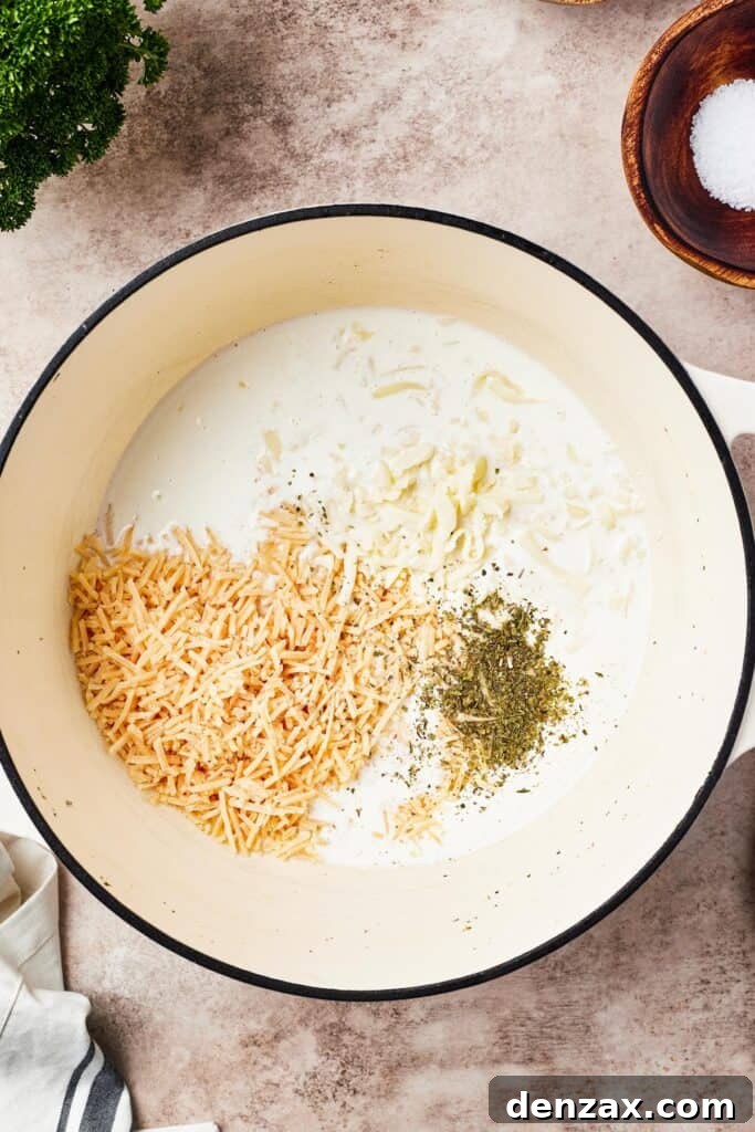 Alfredo sauce being whisked in a large pot.
