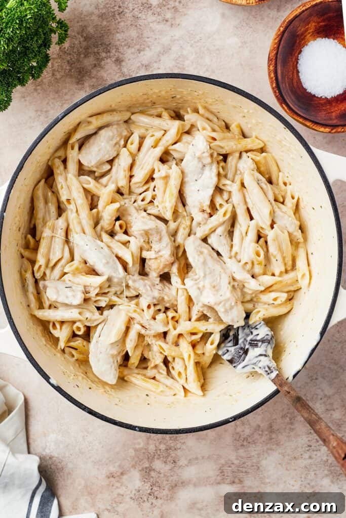 Chicken, pasta, and sauce in a large pot.