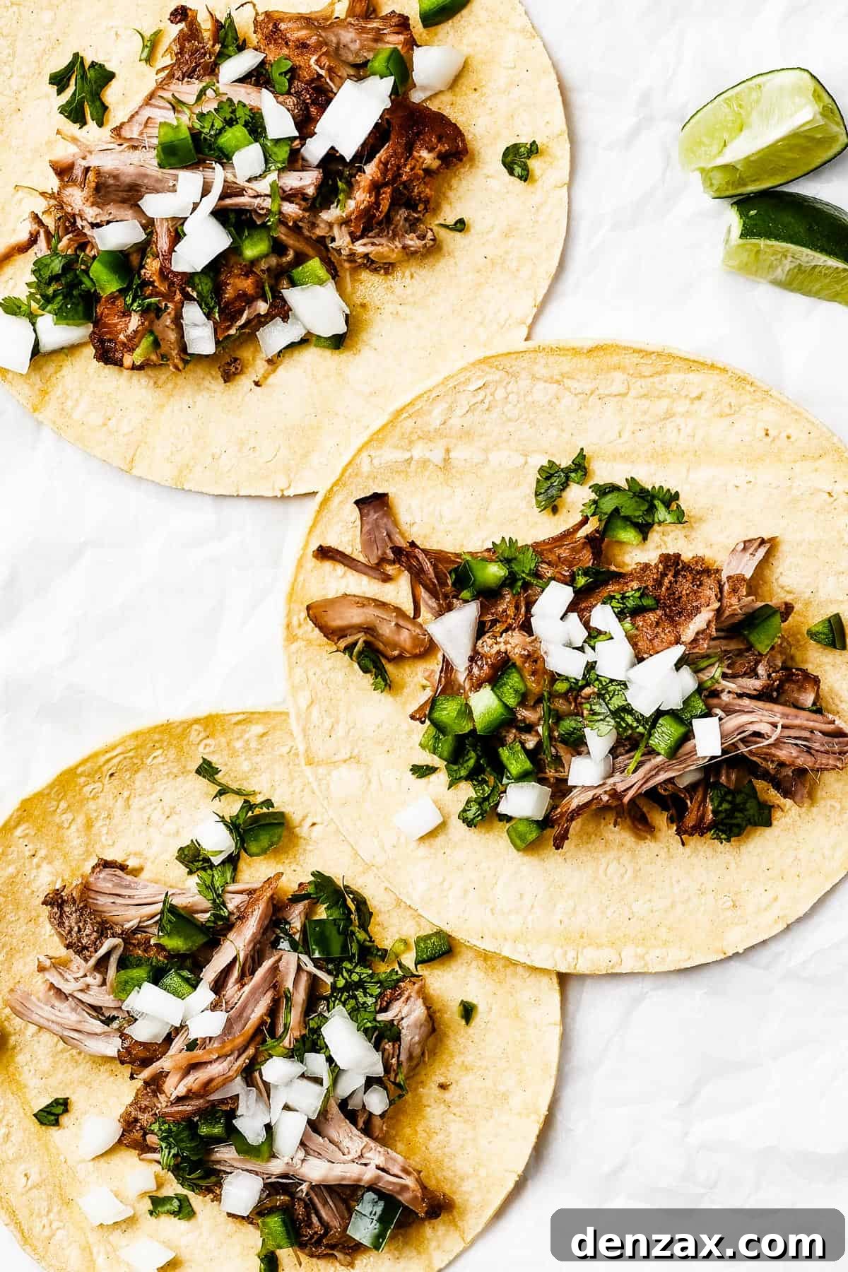 Three tortillas, each with shredded pork and toppings in the center.