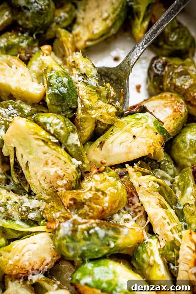 Tender brussels sprouts, slow cooked and tossed with Parmesan cheese. This easy side dish is perfect to serve with meat and potatoes! Halved, cooked brussels sprouts in the slow cooker. A serving spoon is stuck into the sprouts.