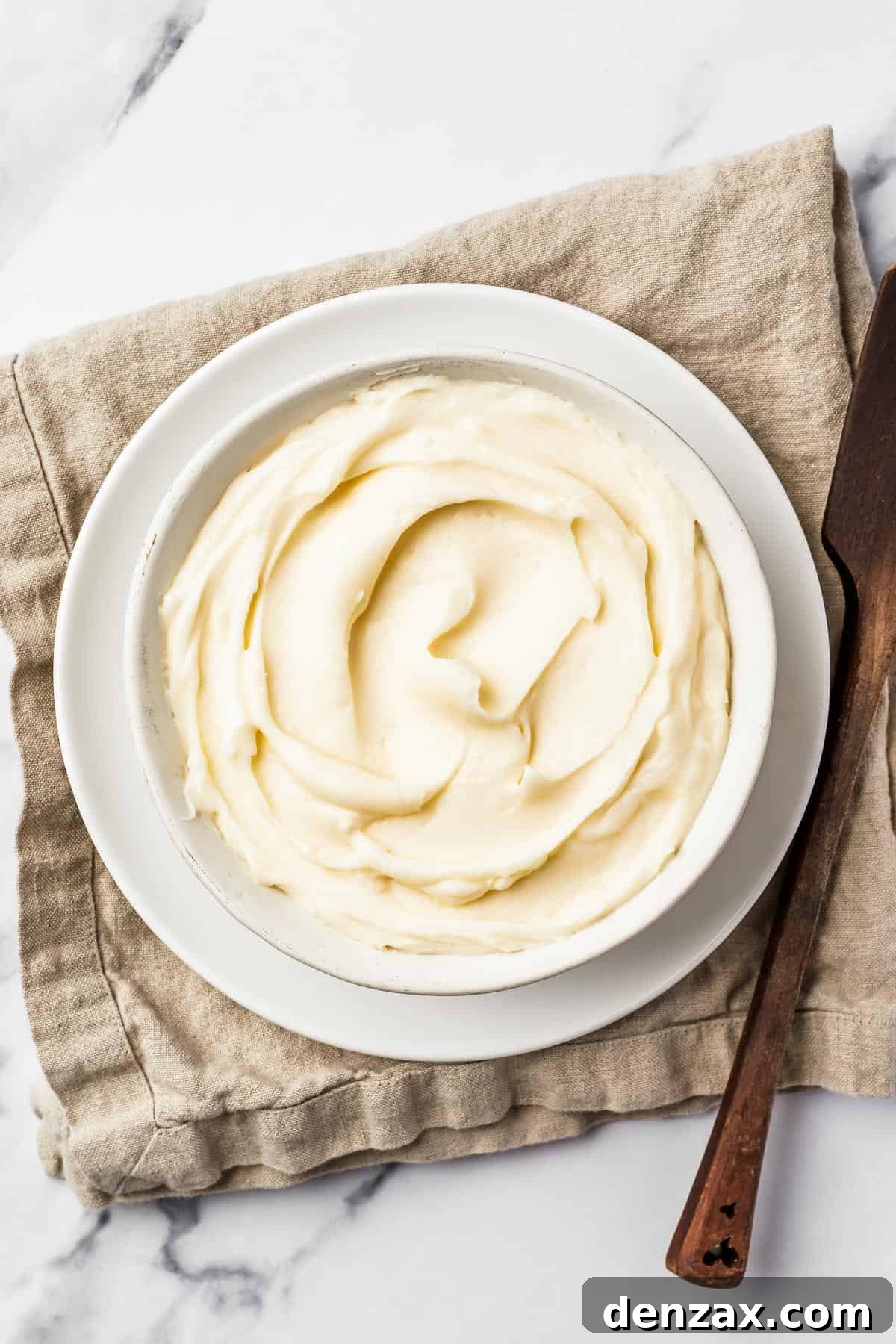 A bowl of creamy white icing on a linen napkin.