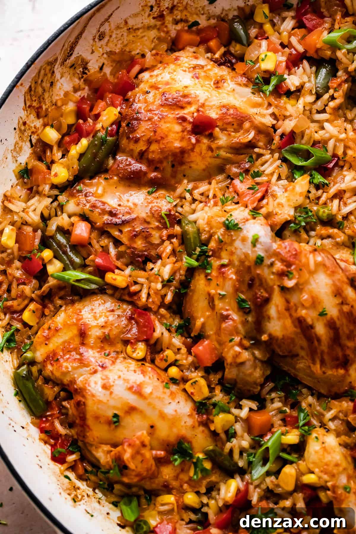 close up overhead shot of a round casserole dish with ranch chicken thighs, rice, and vegetables.