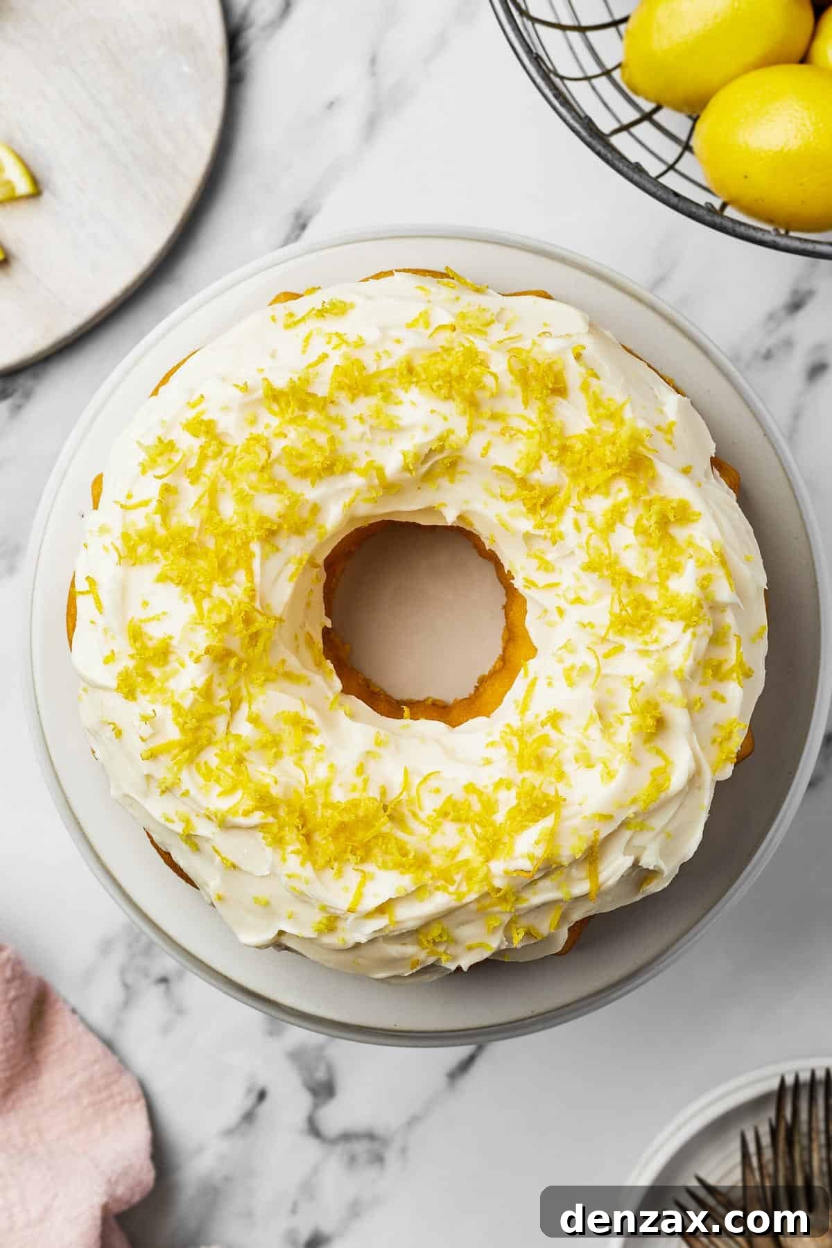 A decorated cake with white frosting and lemon zest on a round white plate.