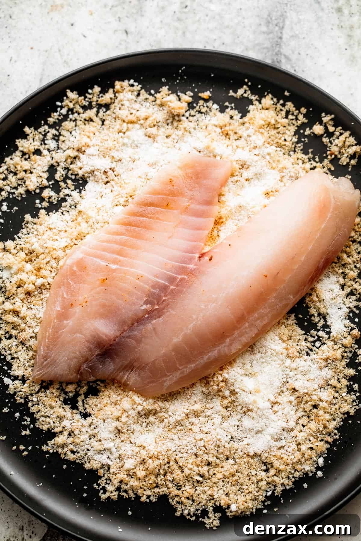 raw tilapia filet placed on top of parmesan bread crumb mixture