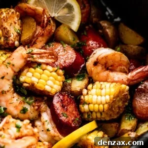 close up shot of corn on the cob rounds, andouille sausage rounds, shrimp, and lemon slices inside of a black air fryer basket.